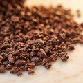 Roasted cocoa nibs scattered on marble showing their dry cracked texture